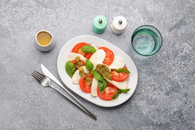 Photo of Tasty salad Caprese served with pesto sauce on grey table, flat lay