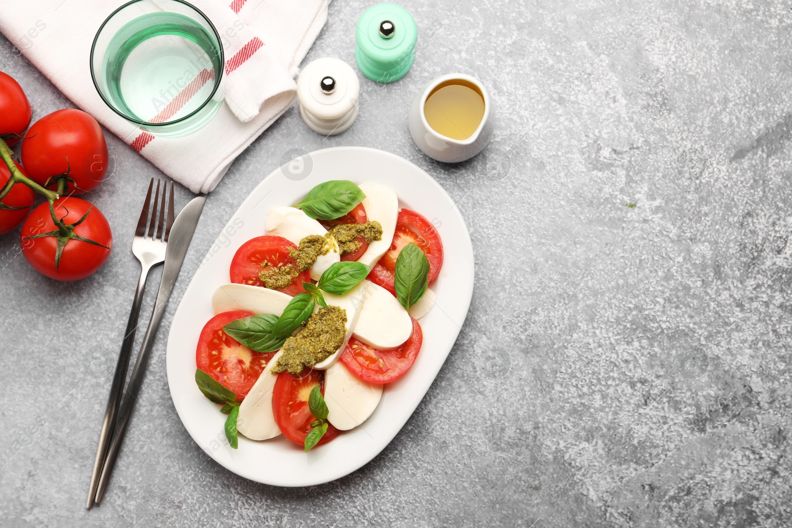 Tasty salad Caprese served with pesto sauce on grey table, flat lay. Space for text Photo of Tasty salad Caprese served with pesto sauce on grey table, flat lay. Space for text