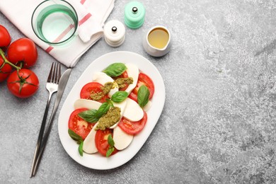 Photo of Tasty salad Caprese served with pesto sauce on grey table, flat lay. Space for text