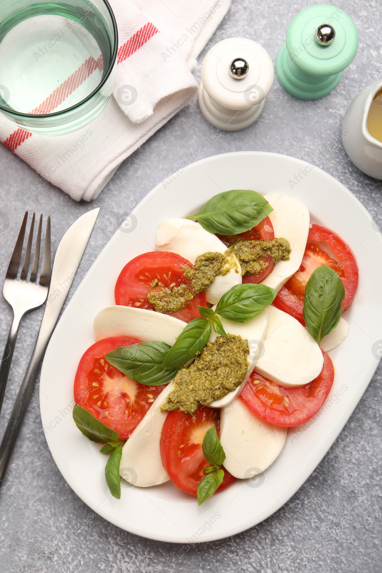Tasty salad Caprese served with pesto sauce on grey table, flat lay Photo of Tasty salad Caprese served with pesto sauce on grey table, flat lay