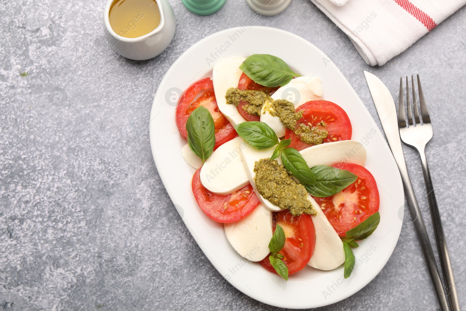 Tasty salad Caprese served with pesto sauce on grey table, flat lay. Space for text Photo of Tasty salad Caprese served with pesto sauce on grey table, flat lay. Space for text