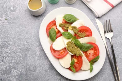 Photo of Tasty salad Caprese served with pesto sauce on grey table, flat lay. Space for text