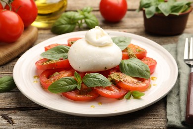 Photo of Tasty salad Caprese served with pesto sauce on wooden table, closeup