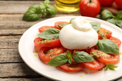 Photo of Tasty salad Caprese served with pesto sauce on wooden table, closeup