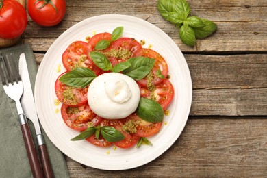 Photo of Tasty salad Caprese served with pesto sauce on wooden table, flat lay. Space for text