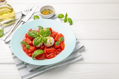 Photo of Tasty salad Caprese with mozzarella, tomatoes, basil and spices on white wooden table, closeup. Space for text