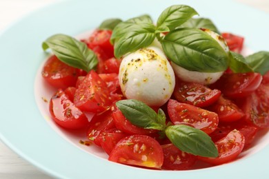 Photo of Tasty salad Caprese with mozzarella, tomatoes, basil and spices on table, closeup