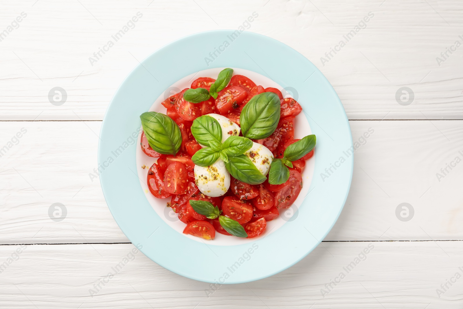 Tasty salad Caprese with mozzarella, tomatoes, basil and spices on white wooden table, top view Photo of Tasty salad Caprese with mozzarella, tomatoes, basil and spices on white wooden table, top view