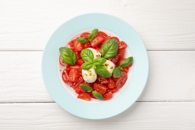 Photo of Tasty salad Caprese with mozzarella, tomatoes, basil and spices on white wooden table, top view