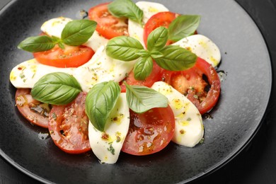 Photo of Tasty salad Caprese with mozzarella, tomatoes, basil and spices on table, closeup
