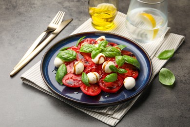 Photo of Tasty salad Caprese served with balsamic vinegar on grey table, closeup