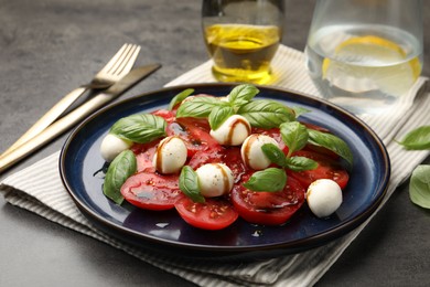 Photo of Tasty salad Caprese served with balsamic vinegar on grey table, closeup