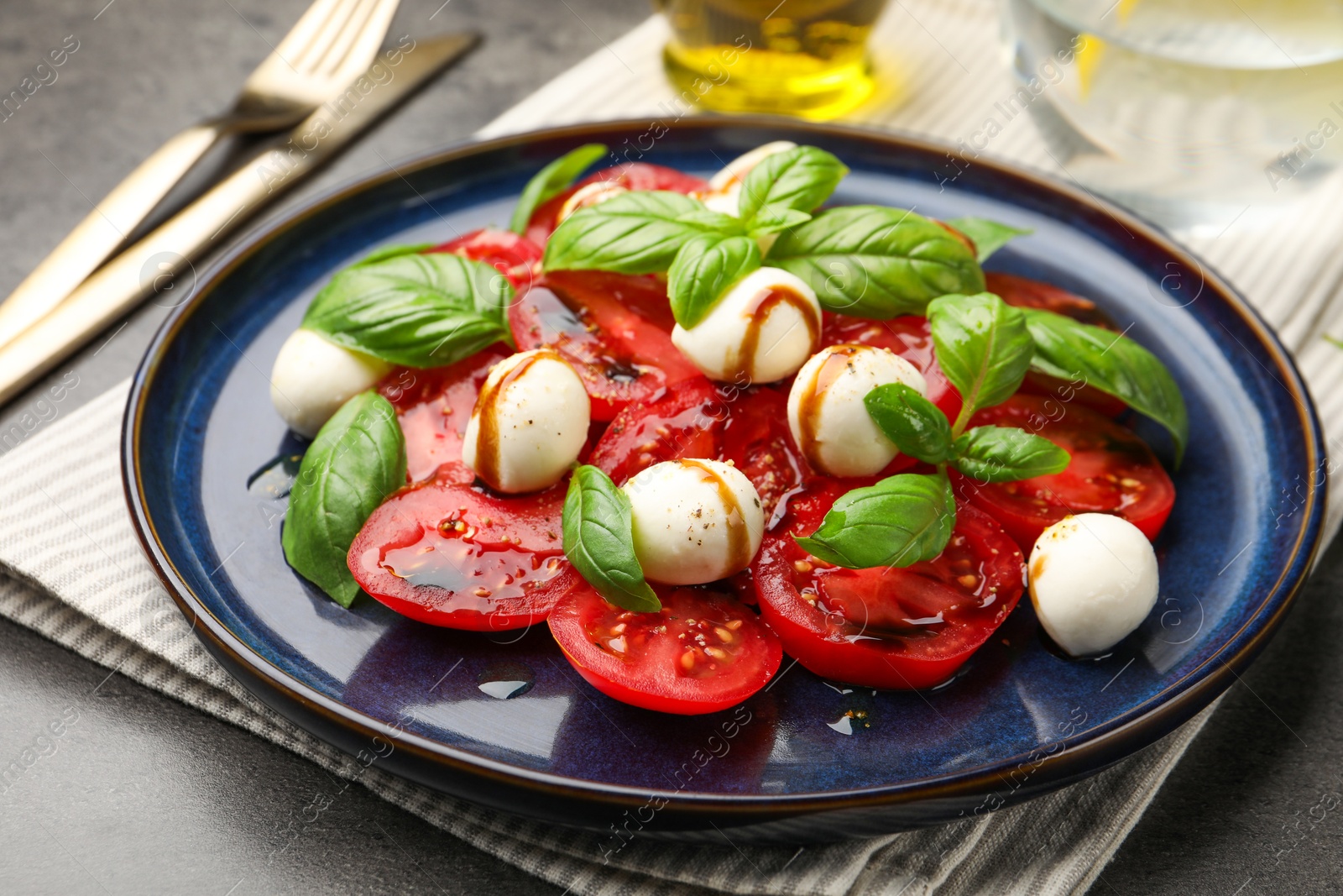 Tasty salad Caprese served with balsamic vinegar on grey table, closeup Photo of Tasty salad Caprese served with balsamic vinegar on grey table, closeup