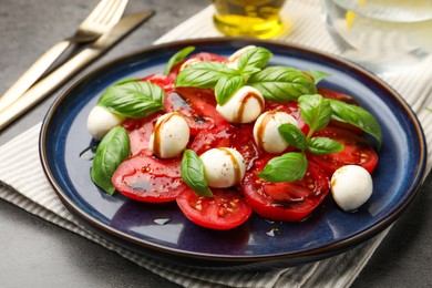 Photo of Tasty salad Caprese served with balsamic vinegar on grey table, closeup