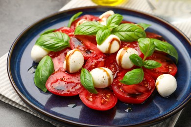 Photo of Tasty salad Caprese with mozzarella, tomatoes, basil and balsamic vinegar on table, closeup
