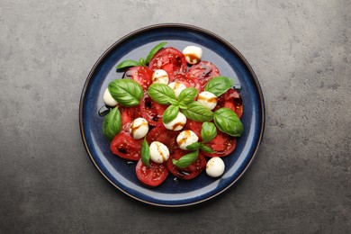 Photo of Tasty salad Caprese with mozzarella, tomatoes, basil and balsamic vinegar on grey table, top view