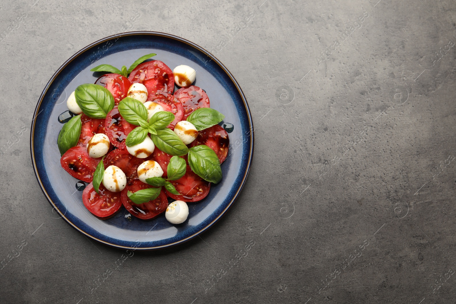Tasty salad Caprese with mozzarella, tomatoes, basil and balsamic vinegar on grey table, top view. Space for text Photo of Tasty salad Caprese with mozzarella, tomatoes, basil and balsamic vinegar on grey table, top view. Space for text