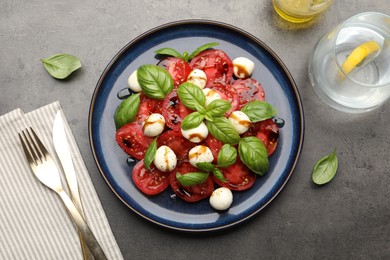 Photo of Tasty salad Caprese served with balsamic vinegar on grey table, flat lay