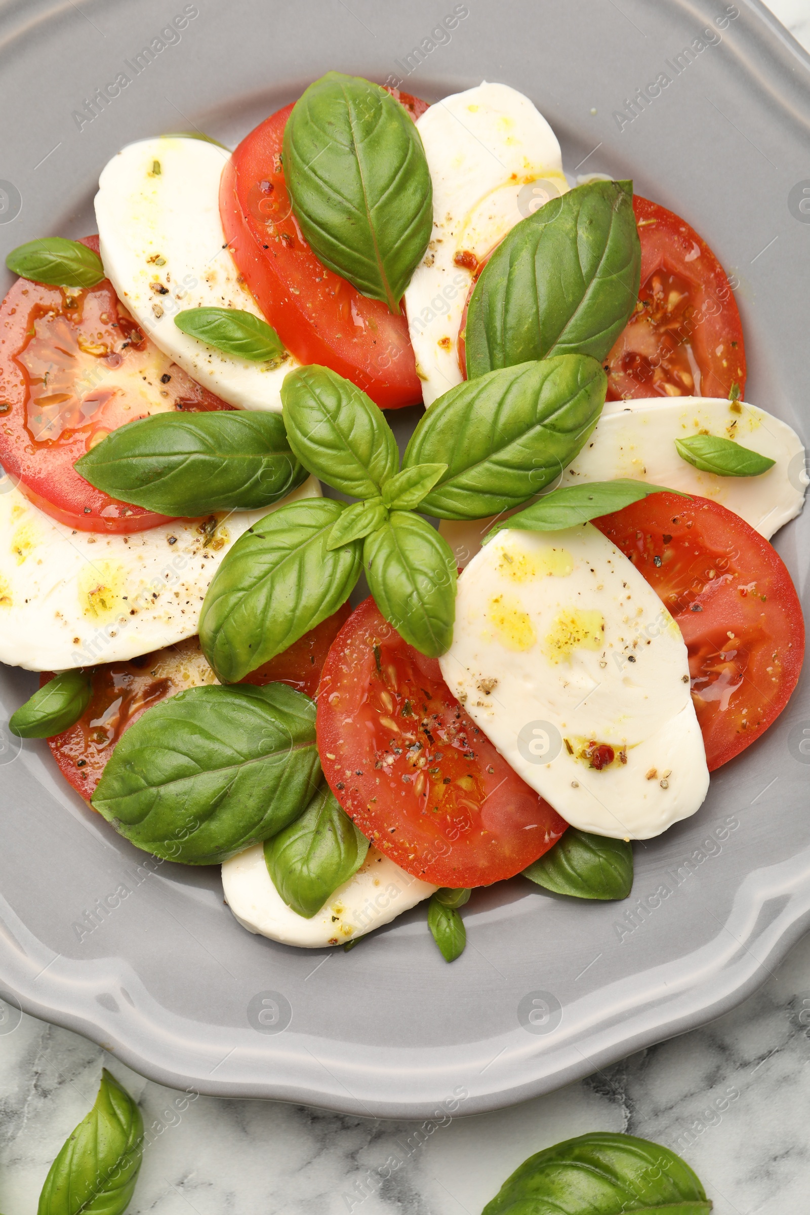 Tasty salad Caprese with mozzarella, tomatoes, basil and spices on white marble table, top view Photo of Tasty salad Caprese with mozzarella, tomatoes, basil and spices on white marble table, top view