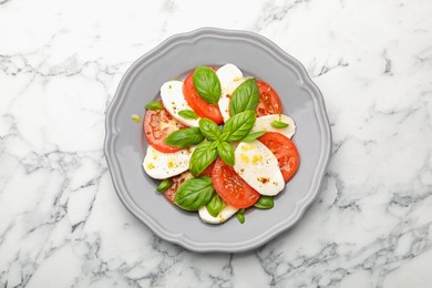 Photo of Tasty salad Caprese with mozzarella, tomatoes, basil and spices on white marble table, top view
