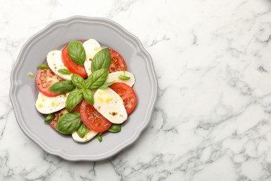 Photo of Tasty salad Caprese with mozzarella, tomatoes, basil and spices on white marble table, top view. Space for text