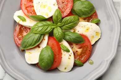 Photo of Tasty salad Caprese with mozzarella, tomatoes, basil and spices on table, top view