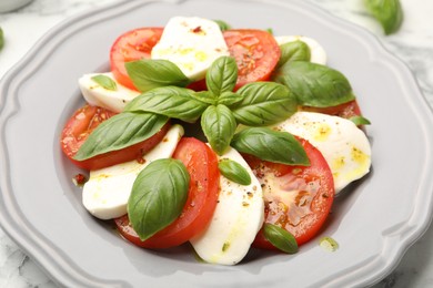 Photo of Tasty salad Caprese with mozzarella, tomatoes, basil and spices on table, closeup