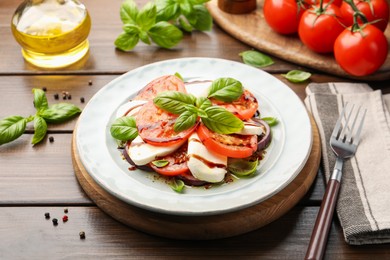 Photo of Tasty salad Caprese with mozzarella, tomatoes, basil and spices on wooden table, closeup