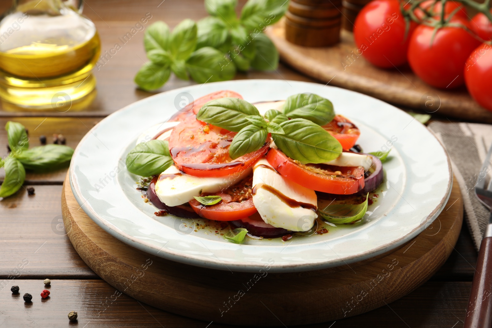 Tasty salad Caprese with mozzarella, tomatoes, basil and spices on wooden table, closeup Photo of Tasty salad Caprese with mozzarella, tomatoes, basil and spices on wooden table, closeup