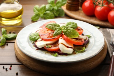 Photo of Tasty salad Caprese with mozzarella, tomatoes, basil and spices on wooden table, closeup