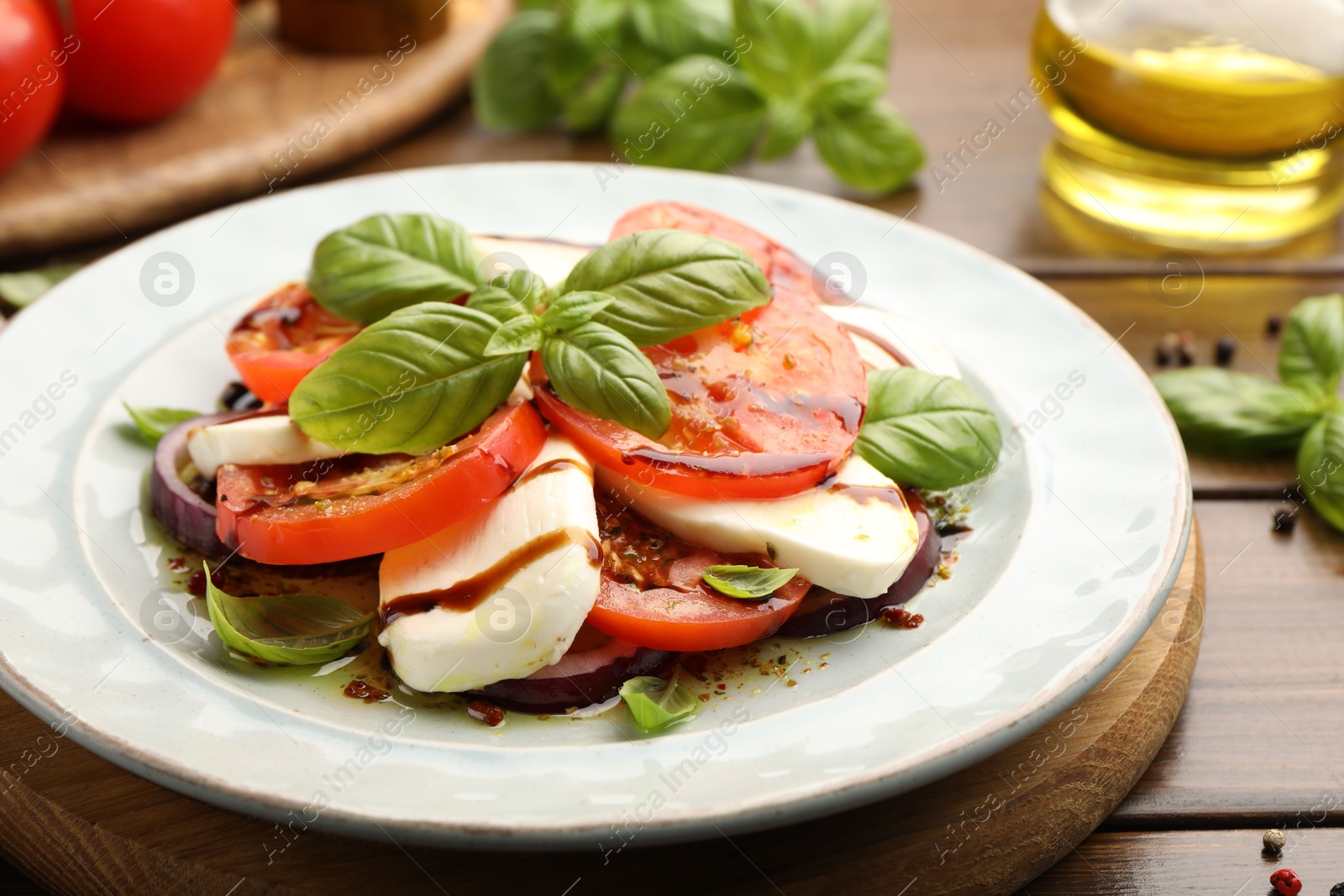 Tasty salad Caprese with mozzarella, tomatoes, basil and spices on wooden table, closeup Photo of Tasty salad Caprese with mozzarella, tomatoes, basil and spices on wooden table, closeup
