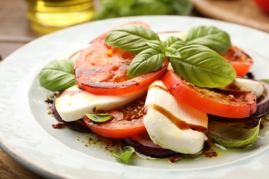 Photo of Tasty salad Caprese with mozzarella, tomatoes, basil and spices on table, closeup
