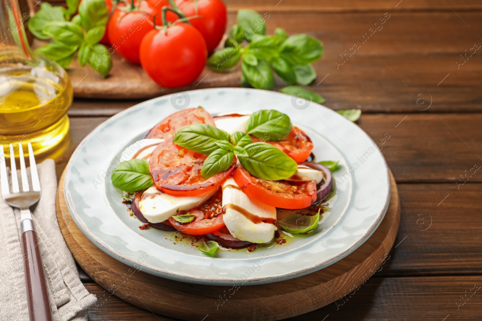 Tasty salad Caprese with mozzarella, tomatoes, basil and spices on wooden table, closeup Photo of Tasty salad Caprese with mozzarella, tomatoes, basil and spices on wooden table, closeup