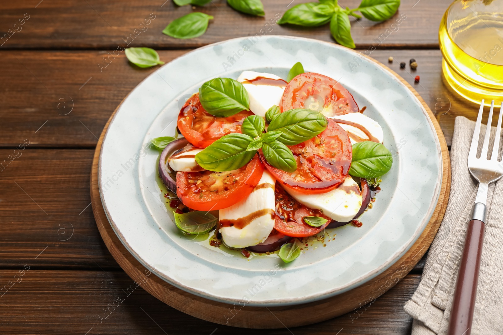 Tasty salad Caprese with mozzarella, tomatoes, basil and spices on wooden table, closeup Photo of Tasty salad Caprese with mozzarella, tomatoes, basil and spices on wooden table, closeup