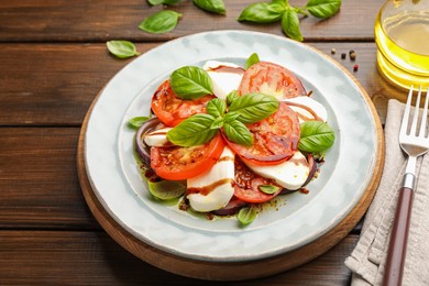Photo of Tasty salad Caprese with mozzarella, tomatoes, basil and spices on wooden table, closeup
