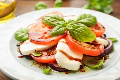 Photo of Tasty salad Caprese with mozzarella, tomatoes, basil and spices on table, closeup