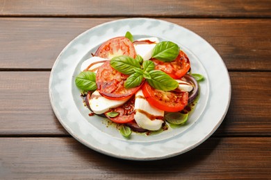 Photo of Tasty salad Caprese with mozzarella, tomatoes, basil and spices on wooden table, closeup