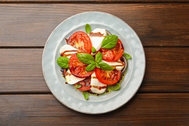 Photo of Tasty salad Caprese with mozzarella, tomatoes, basil and spices on wooden table, top view