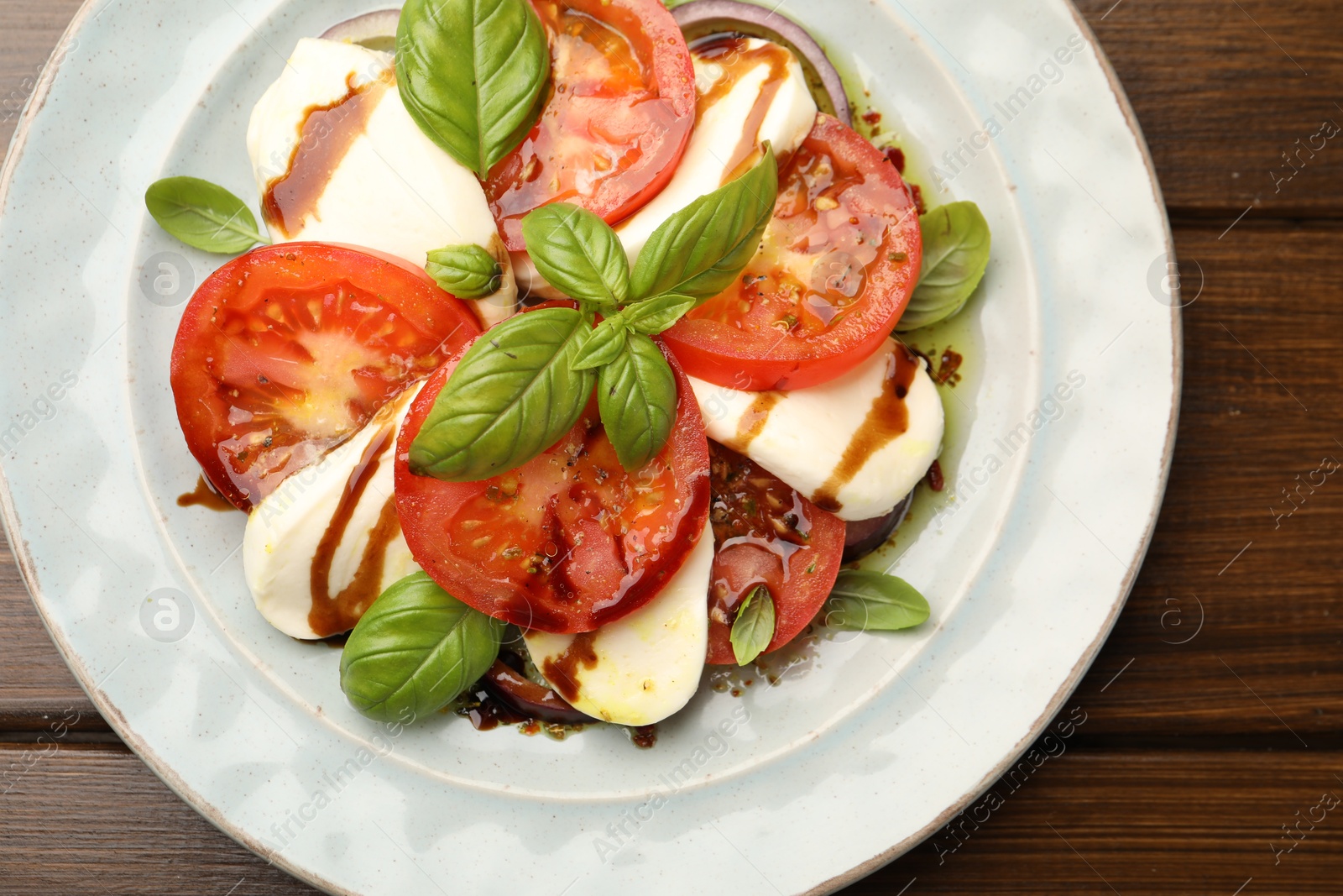Tasty salad Caprese with mozzarella, tomatoes, basil and spices on wooden table, top view Photo of Tasty salad Caprese with mozzarella, tomatoes, basil and spices on wooden table, top view
