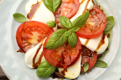 Photo of Tasty salad Caprese with mozzarella, tomatoes, basil and spices on table, top view