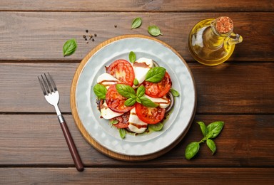 Photo of Tasty salad Caprese served with balsamic vinegar on wooden table, flat lay