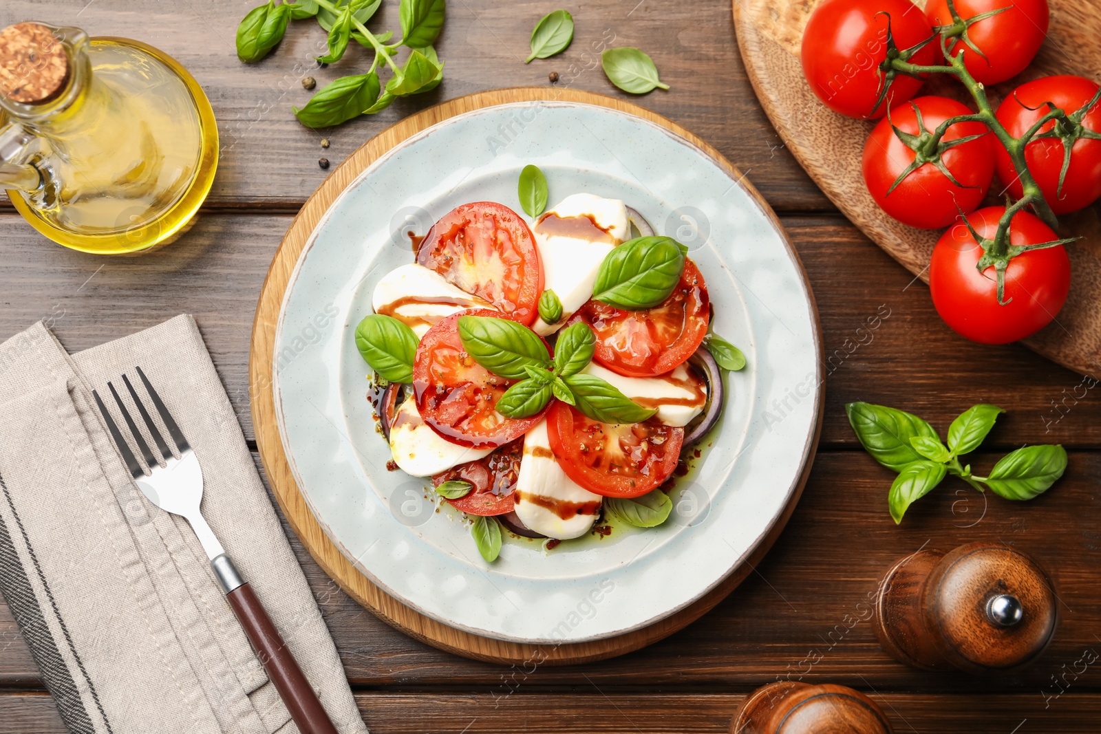 Tasty salad Caprese served with balsamic vinegar on wooden table, flat lay Photo of Tasty salad Caprese served with balsamic vinegar on wooden table, flat lay