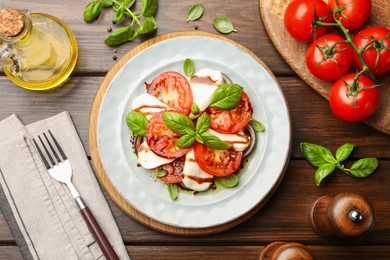 Photo of Tasty salad Caprese served with balsamic vinegar on wooden table, flat lay