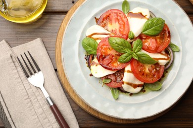 Photo of Tasty salad Caprese served with balsamic vinegar on wooden table, flat lay