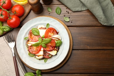 Photo of Tasty salad Caprese served with balsamic vinegar on wooden table, flat lay. Space for text