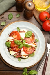 Photo of Tasty salad Caprese served with balsamic vinegar on wooden table, flat lay