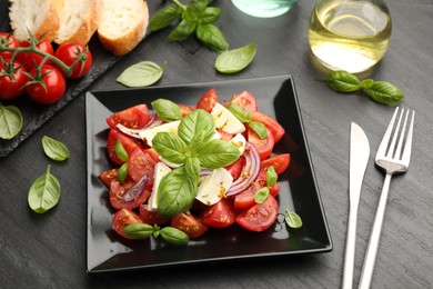 Photo of Tasty salad Caprese served on black table, above view