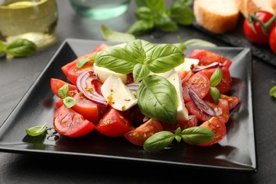 Photo of Tasty salad Caprese served on black table, closeup