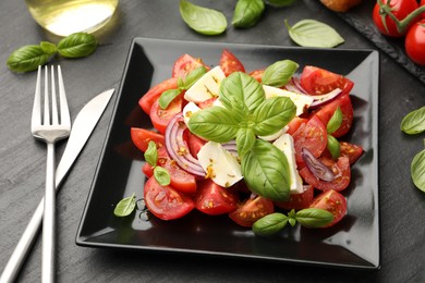 Photo of Tasty salad Caprese served on black table, closeup
