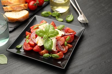 Photo of Tasty salad Caprese served on black table, closeup. Space for text